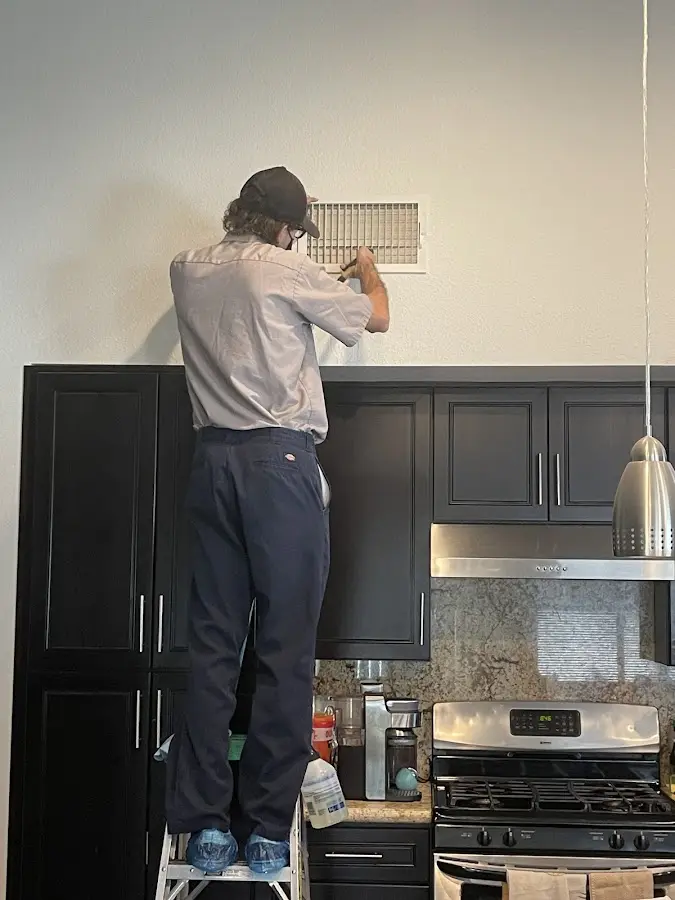 Technician inspecting an air vent during HVAC service in Purcell